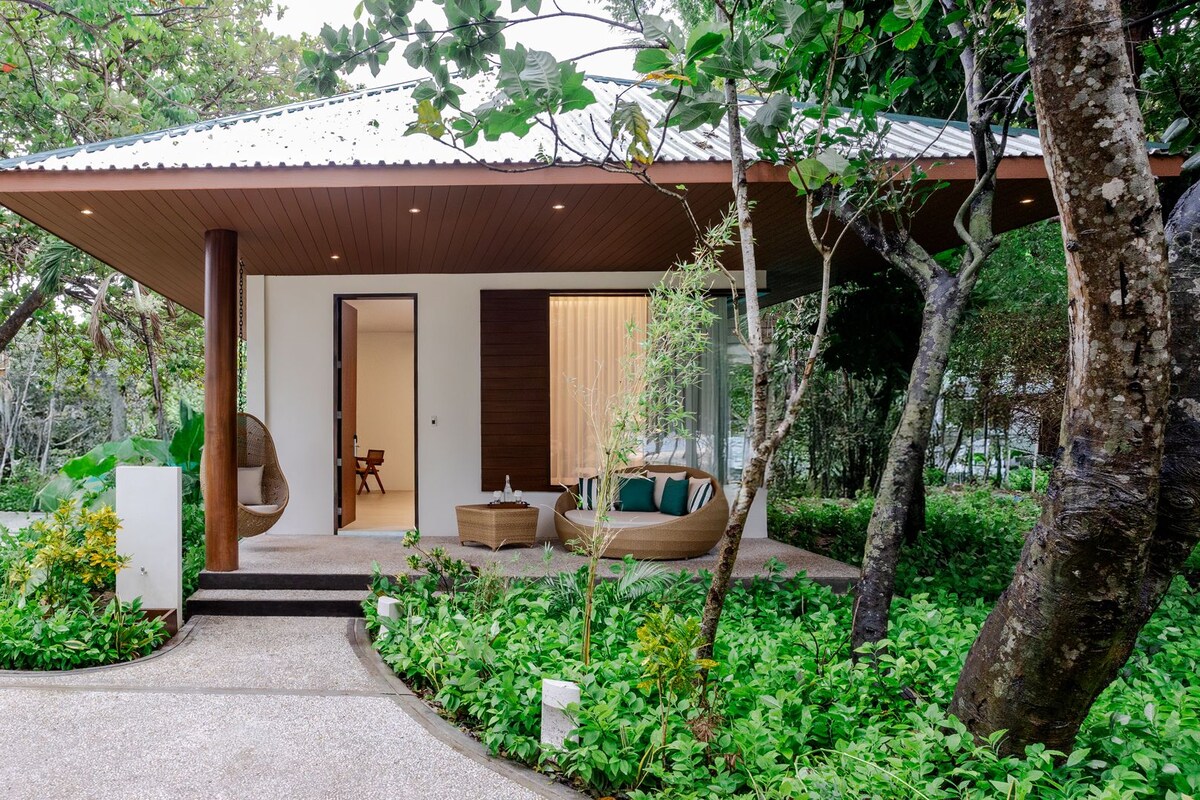 A modern house with a covered porch, a swing chair, and a seating area with cushions.
