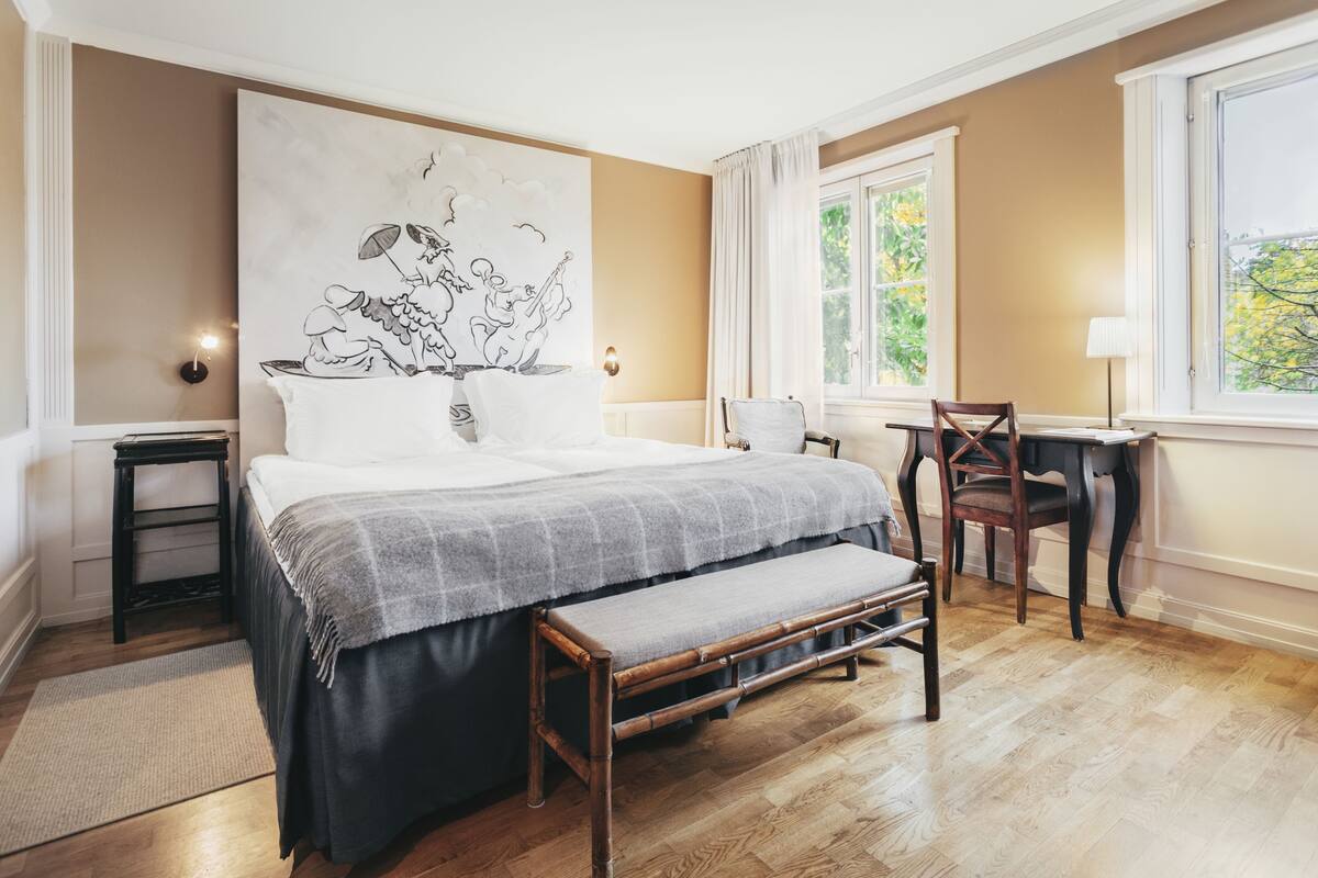 Un dormitorio con una cama grande, un banco de madera, un escritorio y una silla.
