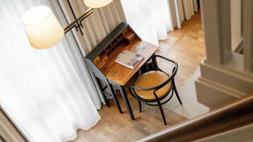 Uma sala de jantar com mesa e cadeiras de madeira, uma luminária e cortinas brancas.