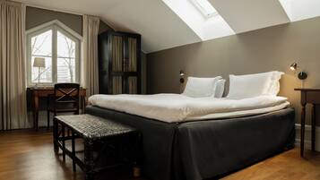 A bedroom with a large bed, a desk, a chair, and a bench.