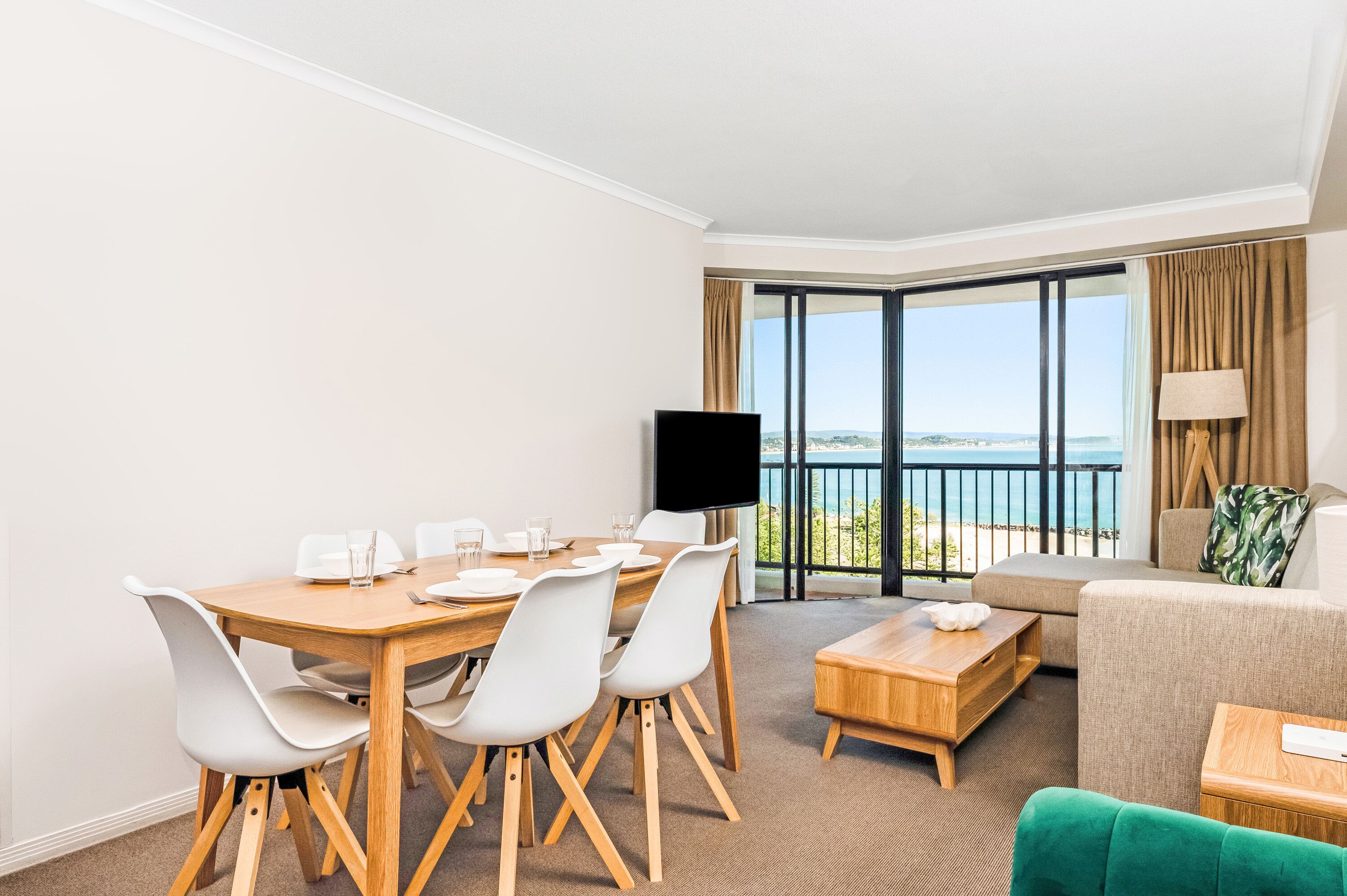 Habitación de hotel con comedor, televisor de pantalla plana, sofá y vista al océano.