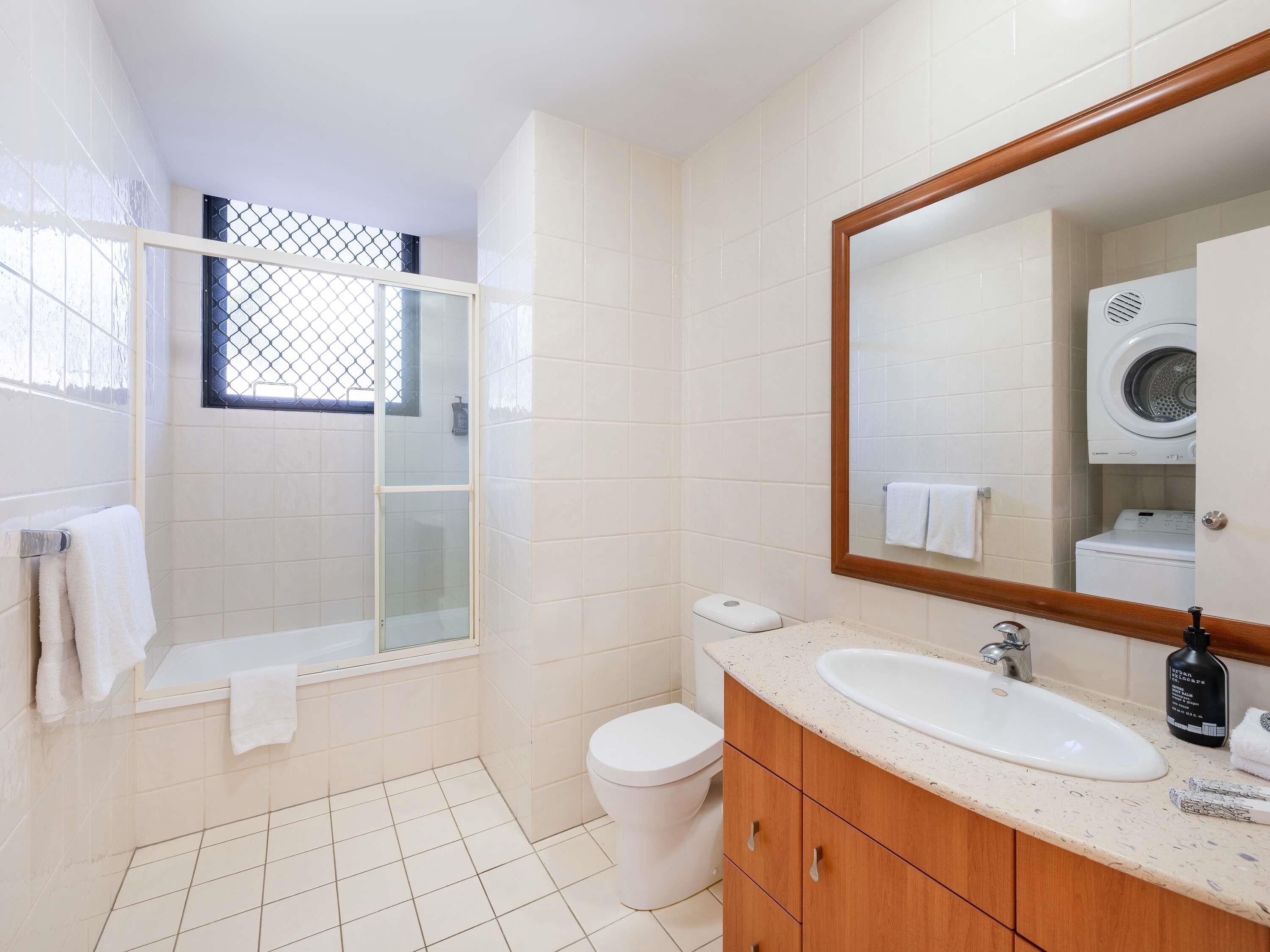 Une salle de bain équipée d’une douche, de toilettes, d’un lavabo et d’un grand miroir.