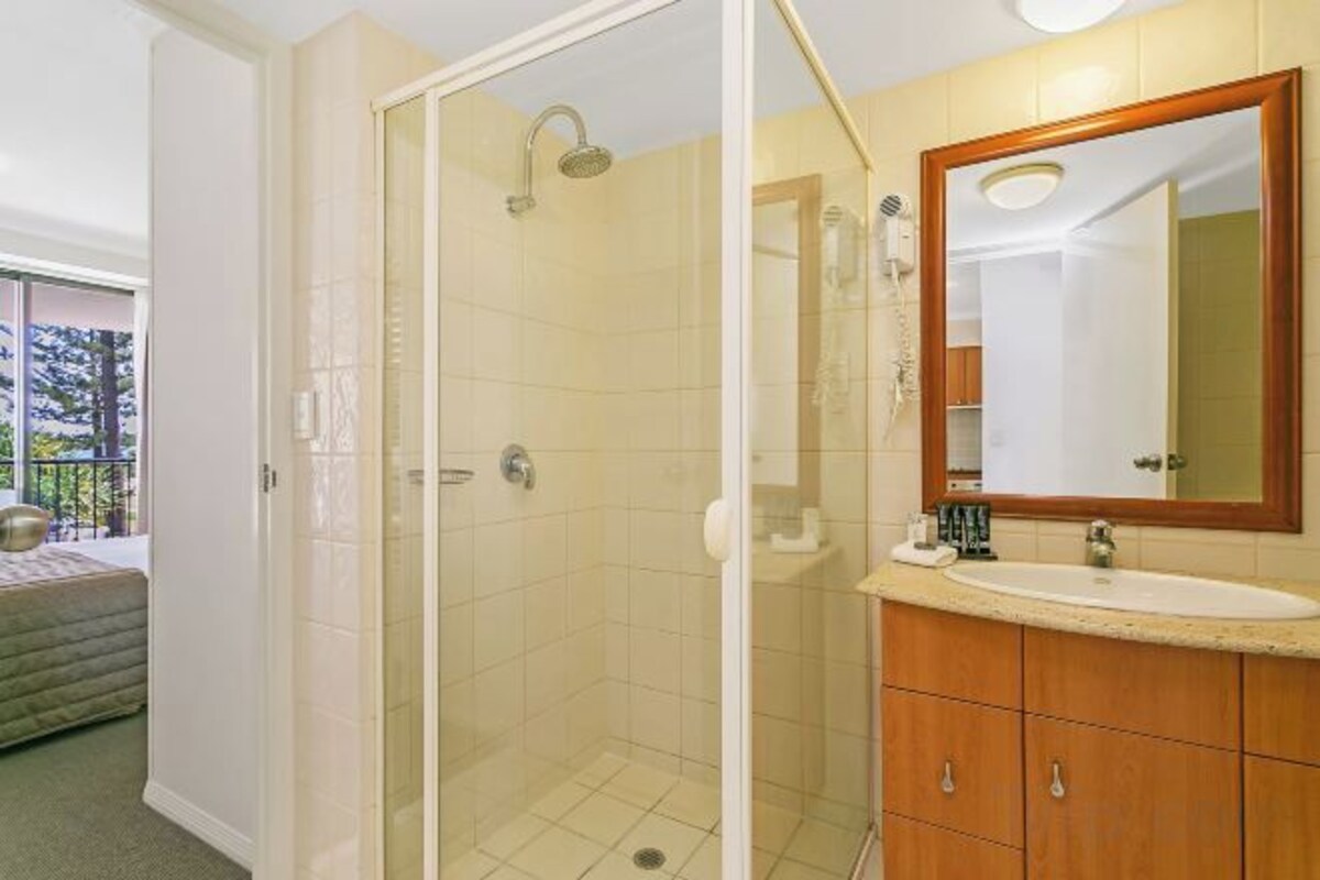 A bathroom with a glass-enclosed shower, a sink, and a mirror.