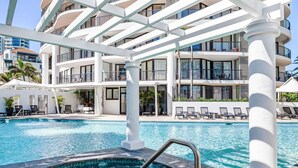 A hotel pool area with a hot tub, lounge chairs, and a multi-story building with balconies. - Mantra Coolangatta Beach (Coolangatta)