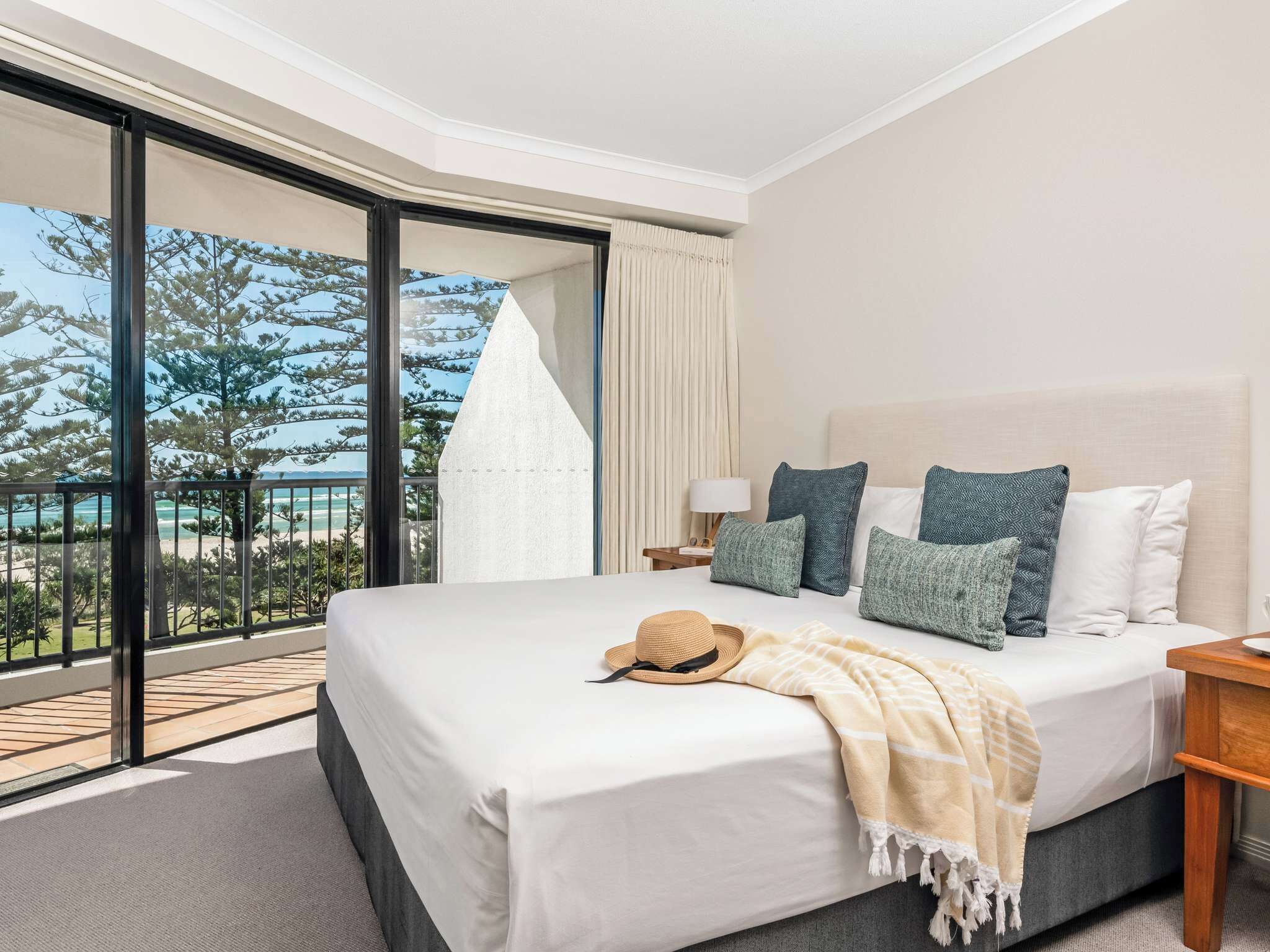 Habitación de hotel con una cama grande, un balcón con vistas y una puerta corrediza de vidrio.