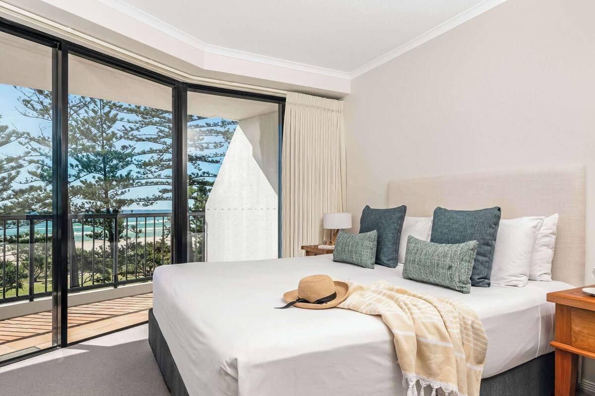 A hotel room with a large bed, a balcony with a view, and a sliding glass door.