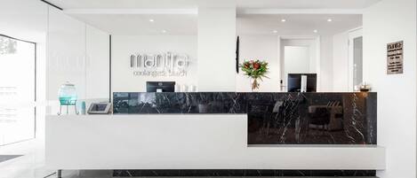 A modern reception desk with a marble top, a glass water dispenser, and a vase with flowers.