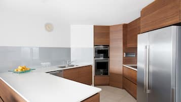 A modern kitchen with wooden cabinets, a stainless steel refrigerator, and a white countertop.