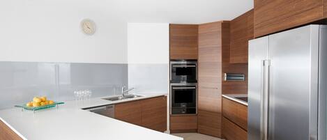 A modern kitchen with wooden cabinets, a stainless steel refrigerator, and a white countertop.
