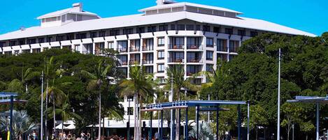 A hotel with a large swimming pool surrounded by palm trees and covered areas.