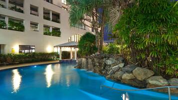 Relax by the serene pool surrounded by lush greenery and a soothing waterfall.