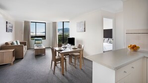 A modern hotel room with a dining area, a sofa, and a view of the mountains. - Mantra Esplanade (Cairns)