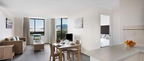 Ett modernt hotellrum med en matplats, en soffa och utsikt över bergen.