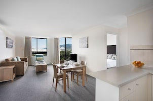 Ett modernt hotellrum med en matplats, en soffa och utsikt över bergen.