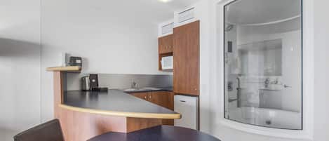 A compact kitchen with a round table, a microwave, and a refrigerator.