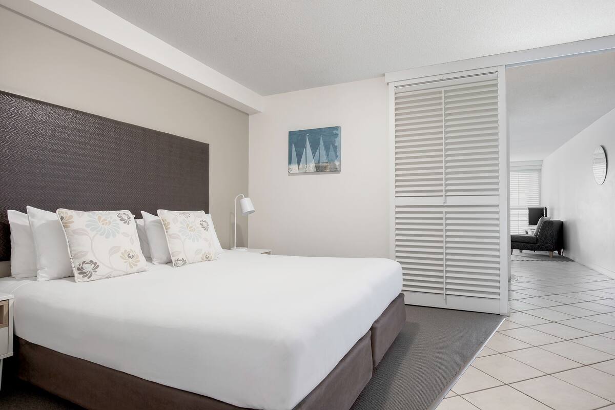 Habitación de hotel con una cama grande, una mesita de noche, un escritorio y una silla.