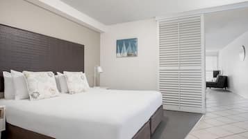 A hotel room with a large bed, a nightstand, a desk, and a chair.