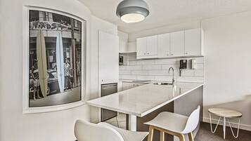 Une cuisine moderne avec des armoires blanches, un grand îlot central et un luminaire suspendu.