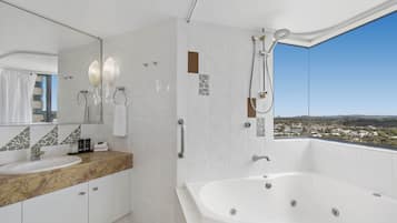 A modern bathroom with a large bathtub, a vanity with a marble countertop, and a large mirror.
