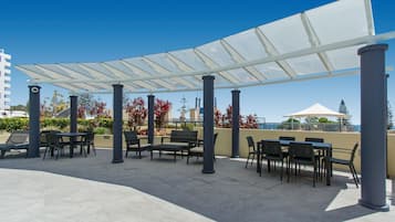 An outdoor patio area with tables and chairs, a canopy, and a view of the cityscape.