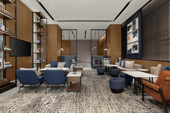 Una biblioteca moderna con estanterías, zonas de estar y una televisión.