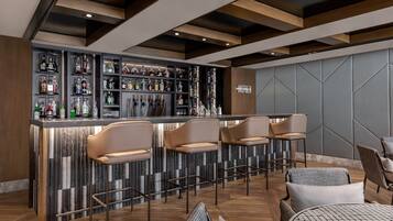 A bar area with a marble countertop, multiple liquor bottles, and bar stools.