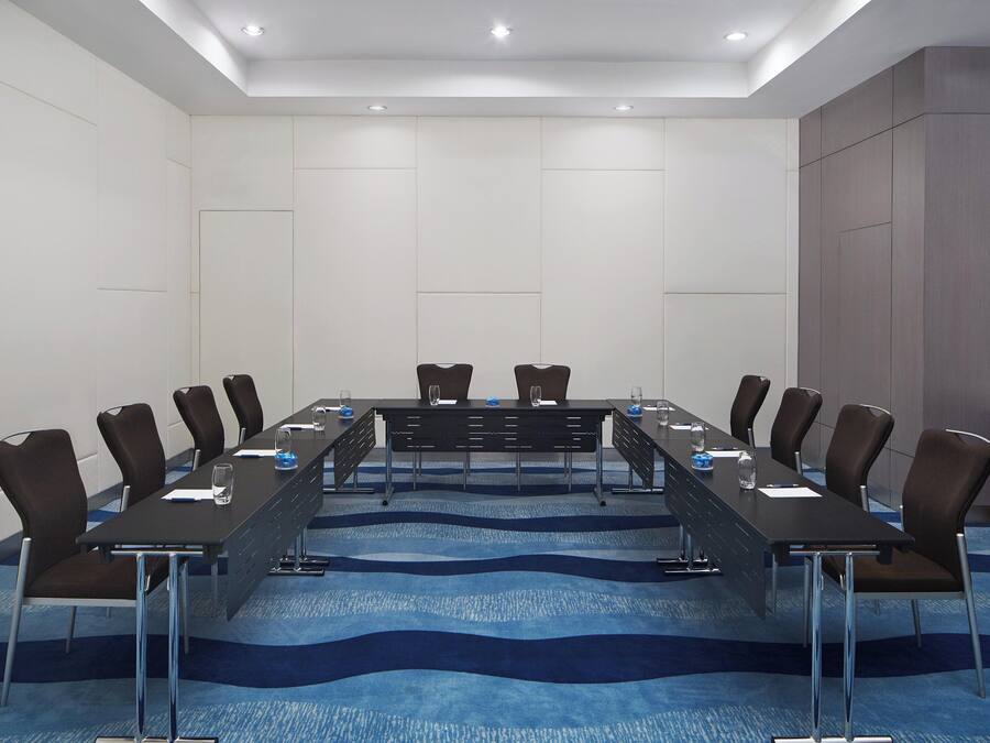 A conference room with a long table, chairs, and a blue carpet.