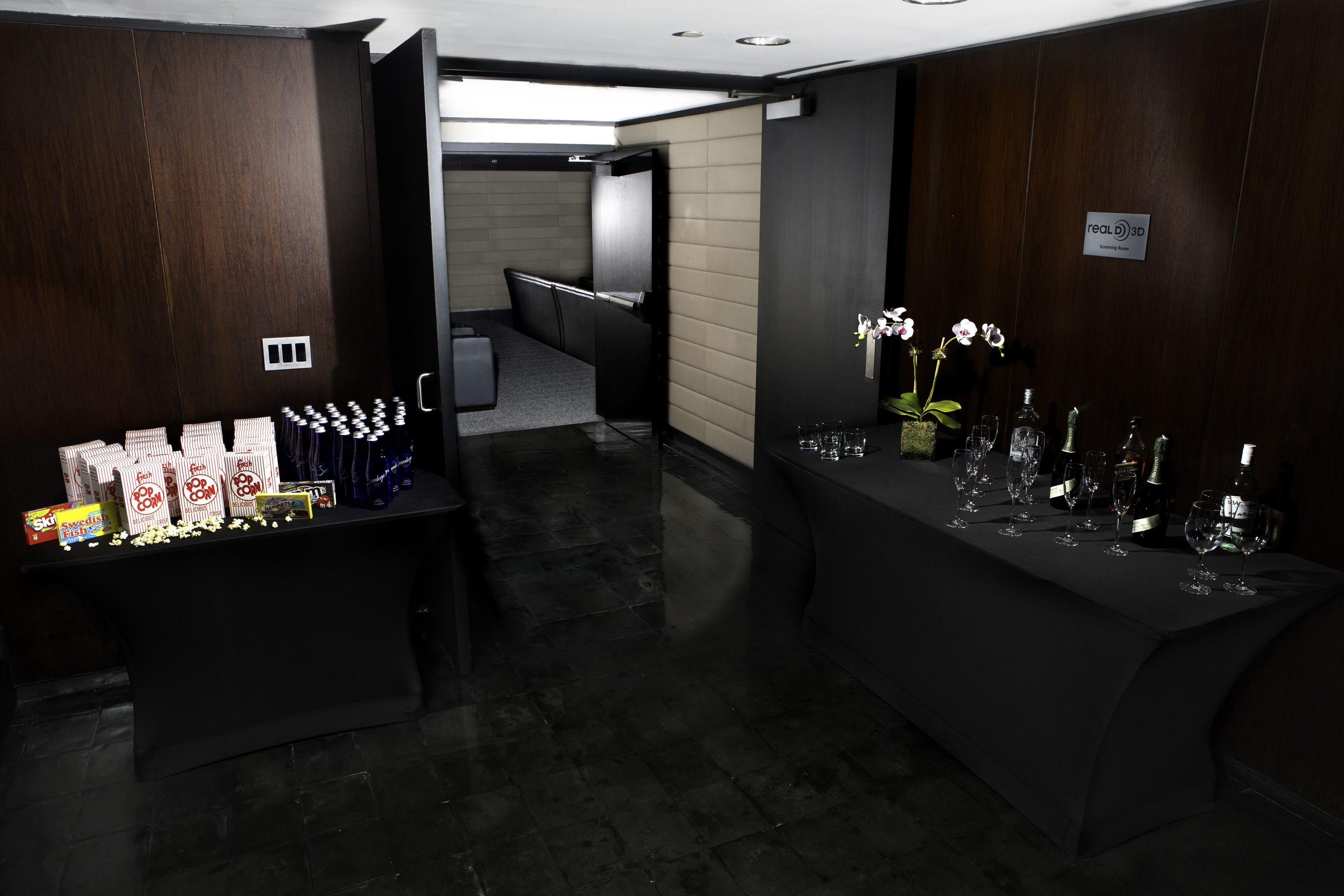 Eine Hotelhalle mit einer Rezeption, einer Sitzecke und einer Bar mit Weingläsern und Flaschen.