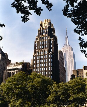A cityscape with prominent high-rise buildings, including a distinctive Art Deco structure and a skyscraper with a spire. - The Bryant Park Hotel (New York)