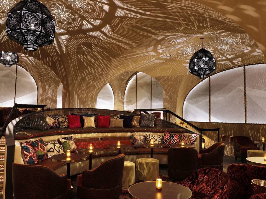 A cozy lounge area with a curved bench, cushioned seating, and ambient lighting.
