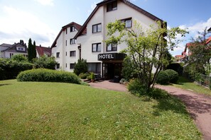 A hotel with a sign, surrounded by well-maintained lawns and bushes. - Hotel Flora Stuttgart - Möhringen (Stuttgart)