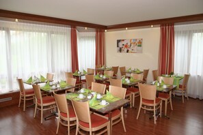 A dining area with multiple tables, chairs, and a painting on the wall. - Hotel Flora Stuttgart - Möhringen (Stuttgart)