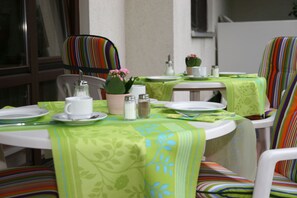 A dining area with green tablecloths, striped chairs, and a small potted plant. - Hotel Flora Stuttgart - Möhringen (Stuttgart)