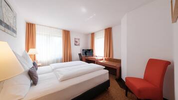 A hotel room with a bed, desk, chair, and a TV.