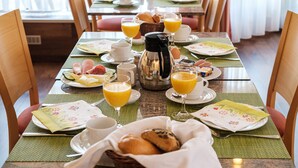 A breakfast setting with a table set for two, including plates, cups, a coffee pot, and a basket of bread. - Hotel Flora Stuttgart - Möhringen (Stuttgart)