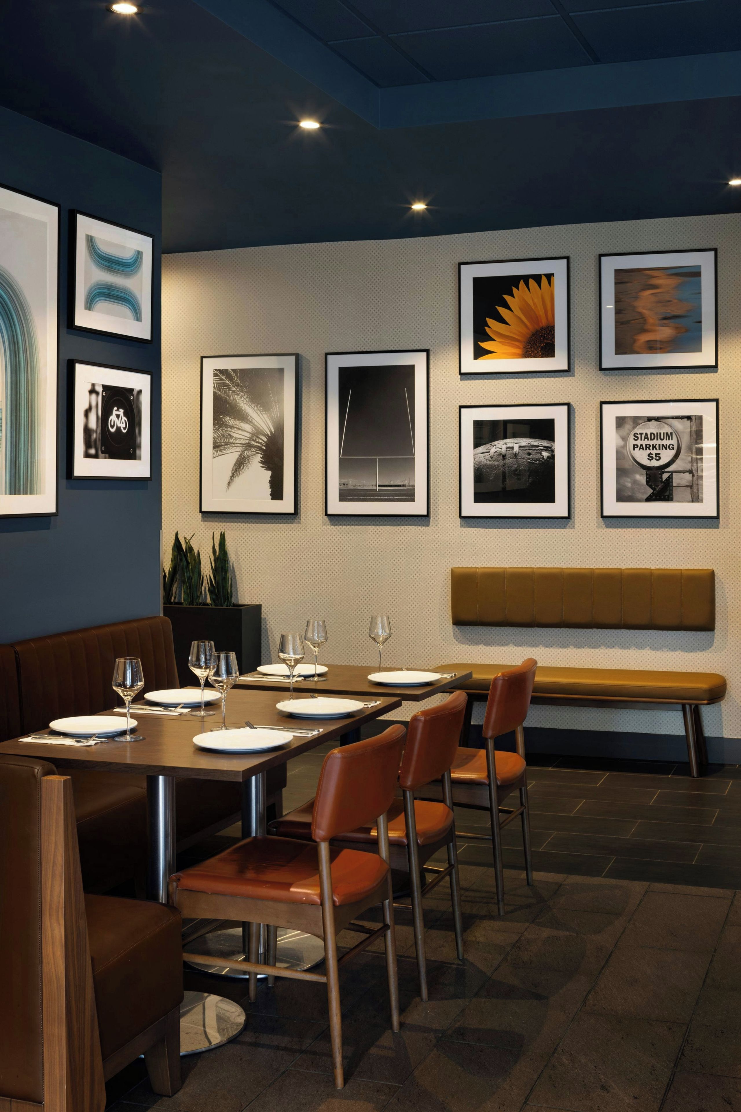 Un restaurante con una larga mesa dispuesta para comer, obras de arte enmarcadas en la pared y un banco al fondo.