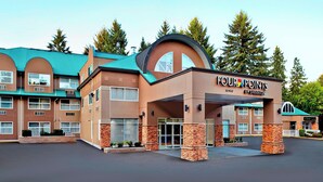 A Four Points by Sheraton hotel with a curved entrance, brick pillars, and a green roof. - Four Points by Sheraton Surrey (Surrey)
