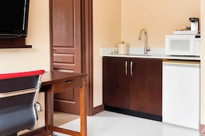 Una cocina compacta con microondas, cafetera y un armario.