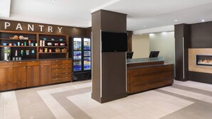 A modern hotel lobby with a wooden pantry counter, a reception desk, and a fireplace. - Four Points by Sheraton Surrey (Surrey)