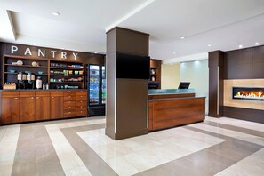 A modern hotel lobby with a pantry area, a reception desk, and a fireplace. - Four Points by Sheraton Surrey (Surrey)