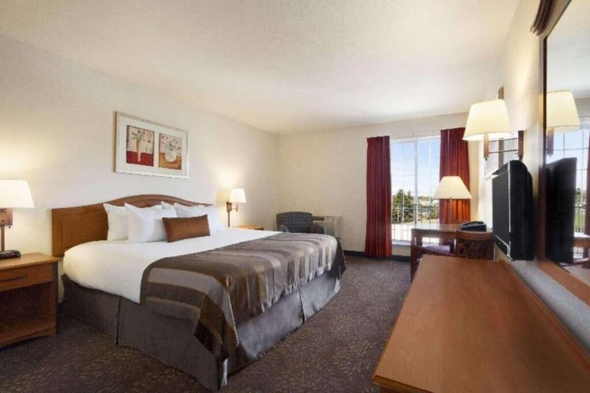 A hotel room with a large bed, a desk, a chair, and a television.