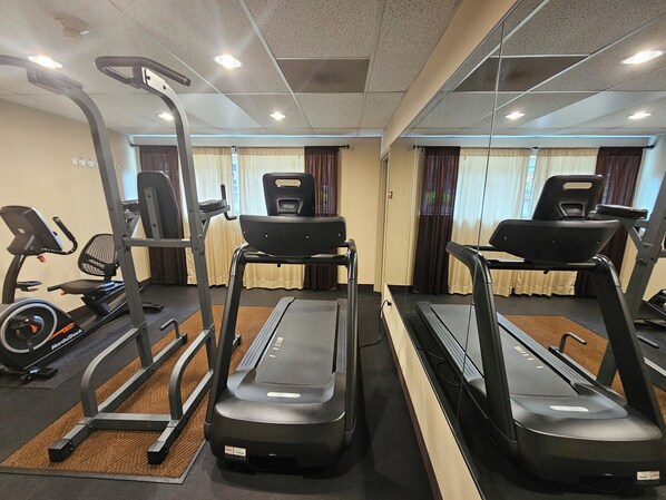 Un gimnasio con cintas de correr, bicicletas estáticas y máquinas de pesas.