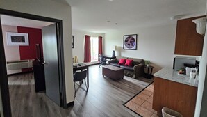 A modern living room with a sofa, coffee table, and a dining area with a table and chairs.