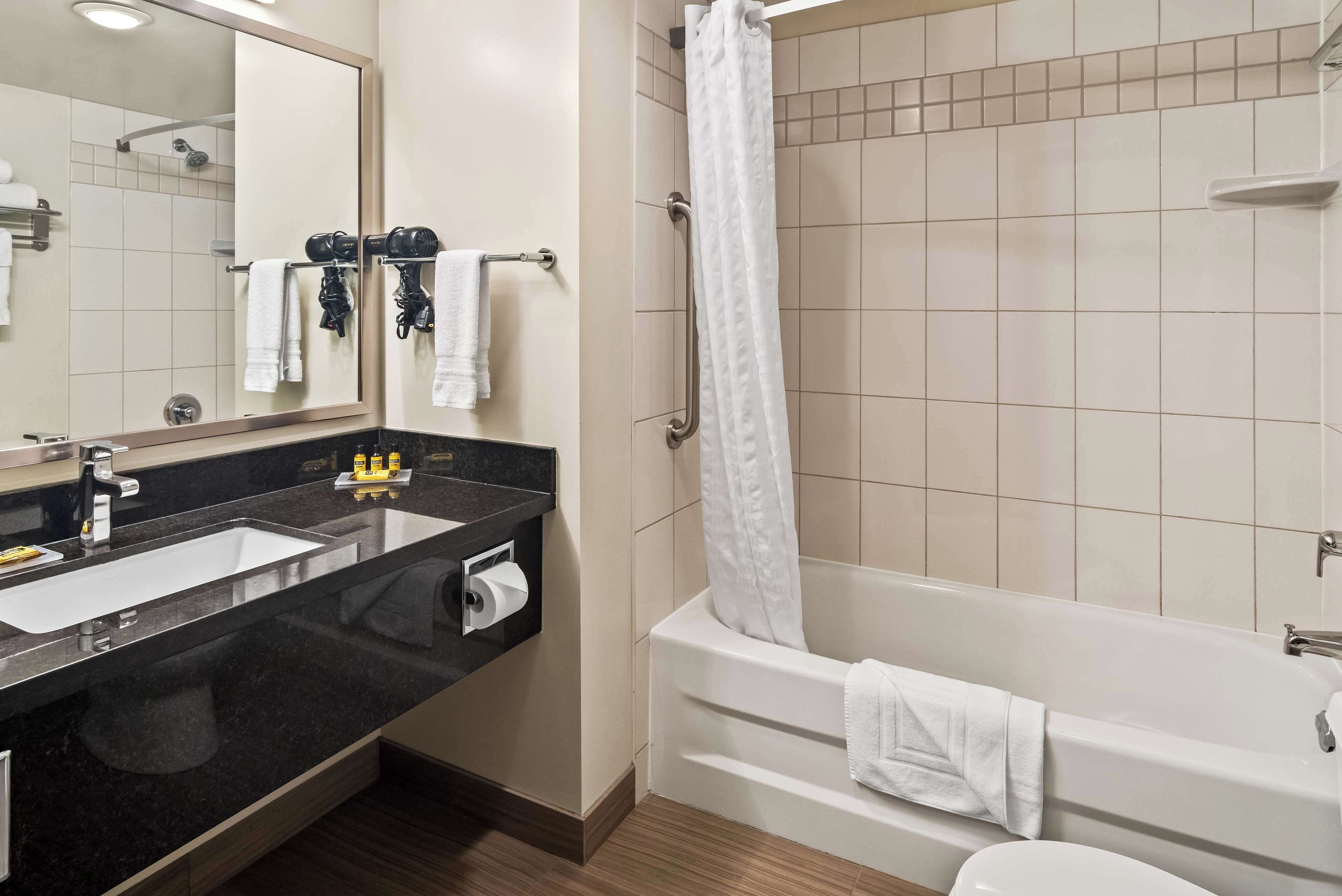 Un baño moderno con lavamanos doble, un espejo grande, una bañera y una cortina de ducha.