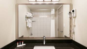 A bathroom with a large mirror, a sink, a towel rack, and a hairdryer.