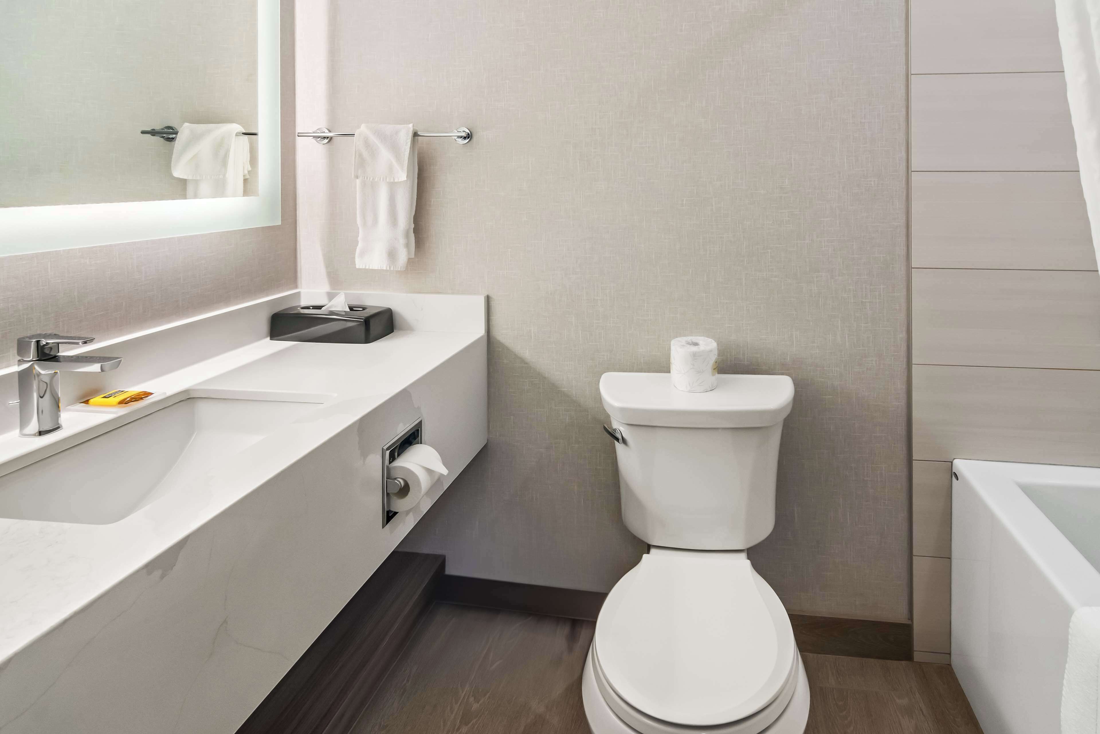 Un baño moderno con lavamanos, inodoro y bañera blancos.