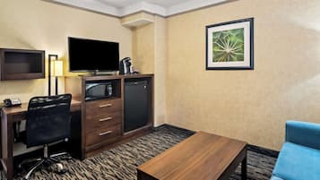 Une chambre d’hôtel équipée d’un bureau, d’une chaise, d’une télévision, d’un mini-réfrigérateur et d’un tableau encadré au mur.