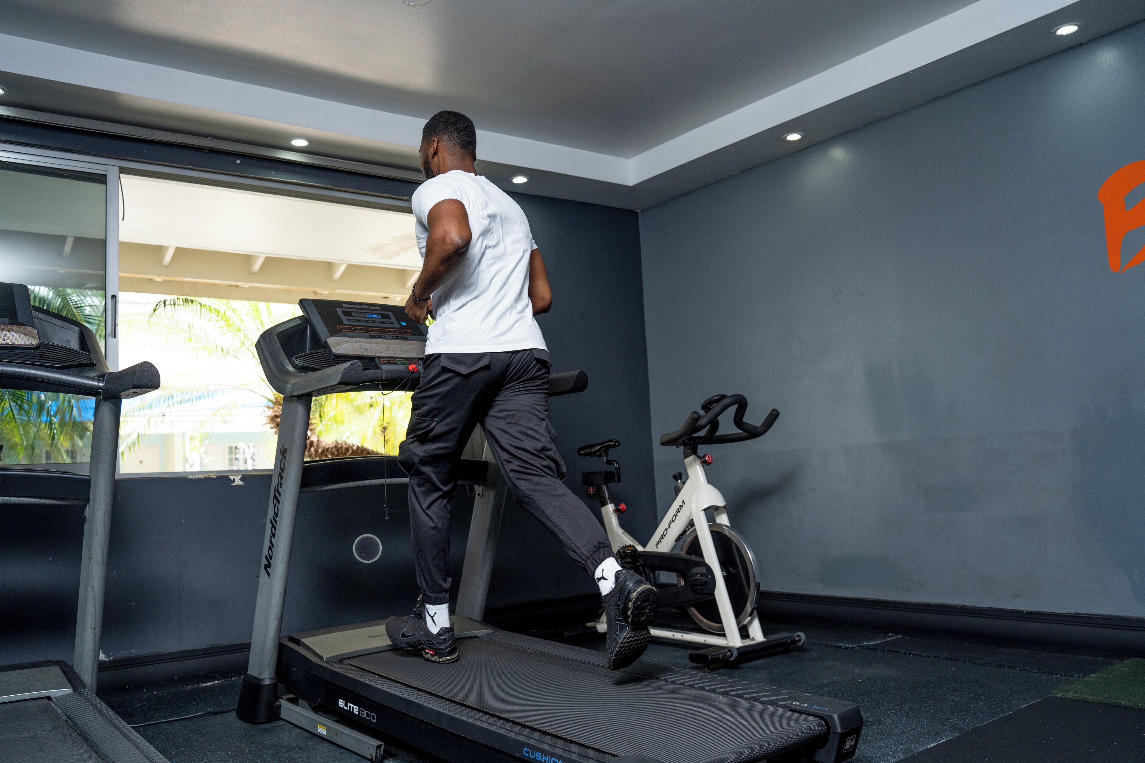 Une salle de sport équipée d’un tapis de course, d’un vélo elliptique et d’un vélo d’appartement.