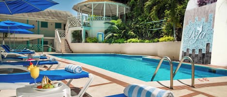 A pool area with lounge chairs, umbrellas, and a water slide.