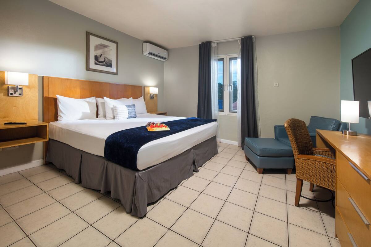 A hotel room with a bed, a desk, a chair, a TV, and a window with curtains.